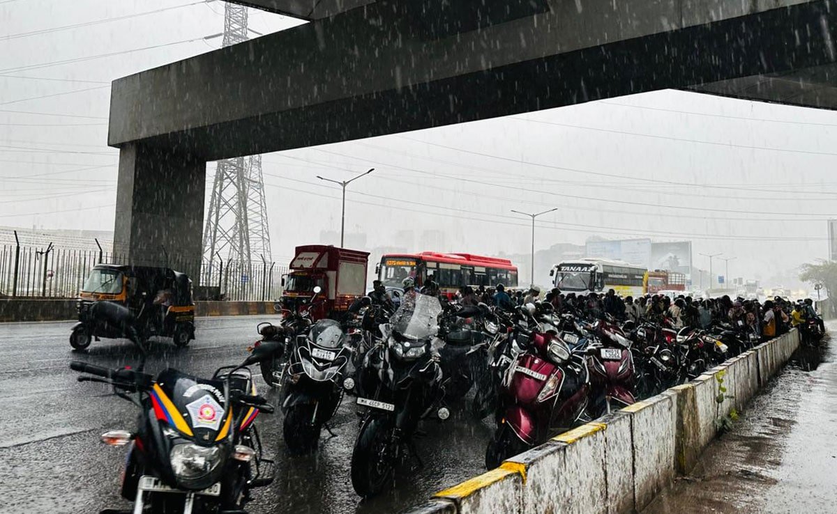 People take cover under a flyover as rainfall hits Mumbai