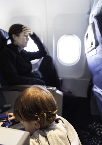 <p>Getty Images</p> A stock photo of a woman and a child on a plane