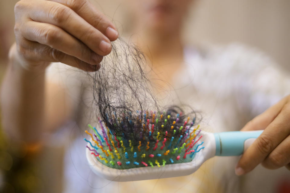 A person holding a hairbrush with a large amount of hair tangled in it