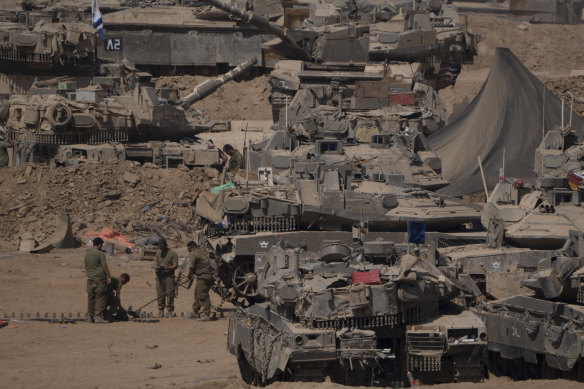 Israeli soldiers work on a tank in a staging area near the Israeli-Gaza border in southern Israel on Monday.