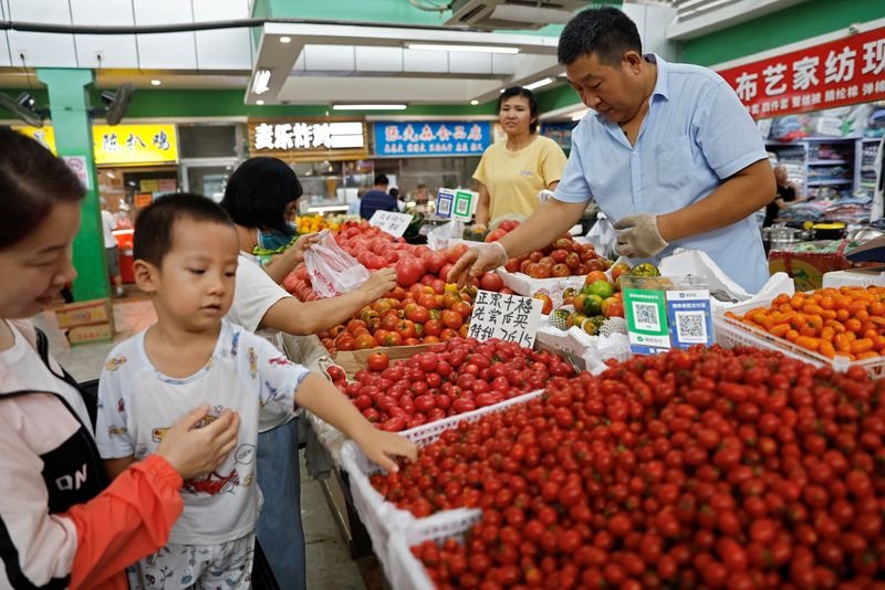 © Reuters. FILE PHOTO: Customers select tomatoes at a stall inside a morning market in Beijing, China August 9, 2023. REUTERS/Tingshu Wang/File Photo