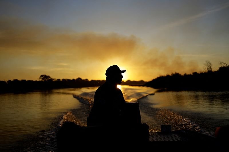 © Reuters. Fisher guide Amilton Brandao sails through the Paraguay River as smoke rises into the air from the fire in the Pantanal, the world's largest wetland, in Corumba, Mato Grosso do Sul state, Brazil, June 11, 2024. REUTERS/Ueslei Marcelino